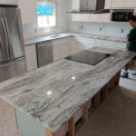 Newly installed granite kitchen countertop with built-in cooktop.