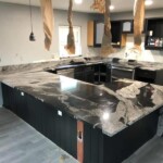 Modern kitchen with black marble countertops and dark cabinetry.