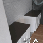 Modern kitchen countertop with white cabinets and dark surface.