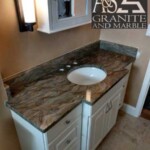 Elegant brown granite countertop with white sink and cabinets.