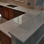 Modern kitchen countertop with sleek, light-colored stone surface.