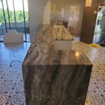A modern kitchen island with a glossy marble countertop and patterned floor tiles.