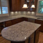 Granite kitchen island with rounded edge and pendant lights.