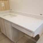 White marble countertop with built-in sink and white cabinets.