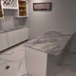 Modern kitchen island with marble countertop and white cabinetry.
