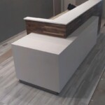 Modern white reception desk with wooden accent on laminate flooring.