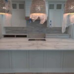 Modern kitchen with marble countertops and pendant lights.