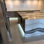 Modern kitchen with sleek marble island and under-cabinet lighting.