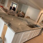 Newly installed kitchen island with marble countertop and white cabinets.