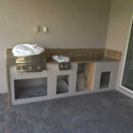 Outdoor built-in grill station with countertop and storage space.