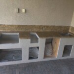 Unfinished concrete kitchen countertop with built-in shelves and spaces for appliances.