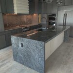 Modern kitchen with a sleek stone island and dark cabinetry.
