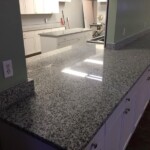 Shiny granite kitchen countertop reflecting light.