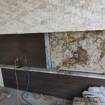 Modern kitchen backsplash installation with marble and wood textures.