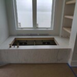 Modern kitchen island with built-in stovetop and white marble finish.