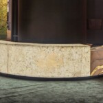 Curved stone bench in a shaded outdoor area.