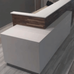 Modern reception desk with wood and white finishes in a sleek office setting.