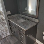 Modern bathroom vanity with marble countertop and gray cabinets.