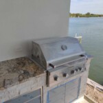 Outdoor grill setup by the water with granite countertop.