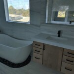 Modern bathroom with freestanding tub and marble countertop vanity.