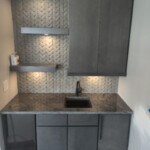 Modern kitchenette with dark cabinets and a sleek black sink.