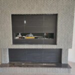 Modern fireplace with dark tiles and a wide glass front.