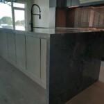 Modern kitchen island with dark stone countertop and cabinetry.