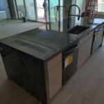 Modern kitchen island with dark countertops and sleek fixtures.