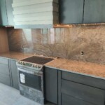 Modern kitchen with dark cabinetry and stone countertops.
