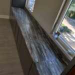 Marble countertop installed beneath two windows in a modern room.