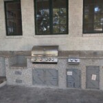 Outdoor kitchen area with built-in grill and stone countertops.