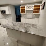Modern kitchen island with marble countertop and white cabinetry.