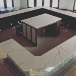 Modern marble kitchen countertop with built-in stove and seating area.