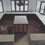 Modern kitchen island with marble countertops and large windows.