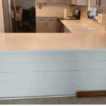White kitchen island with clean countertop and gray shiplap base.